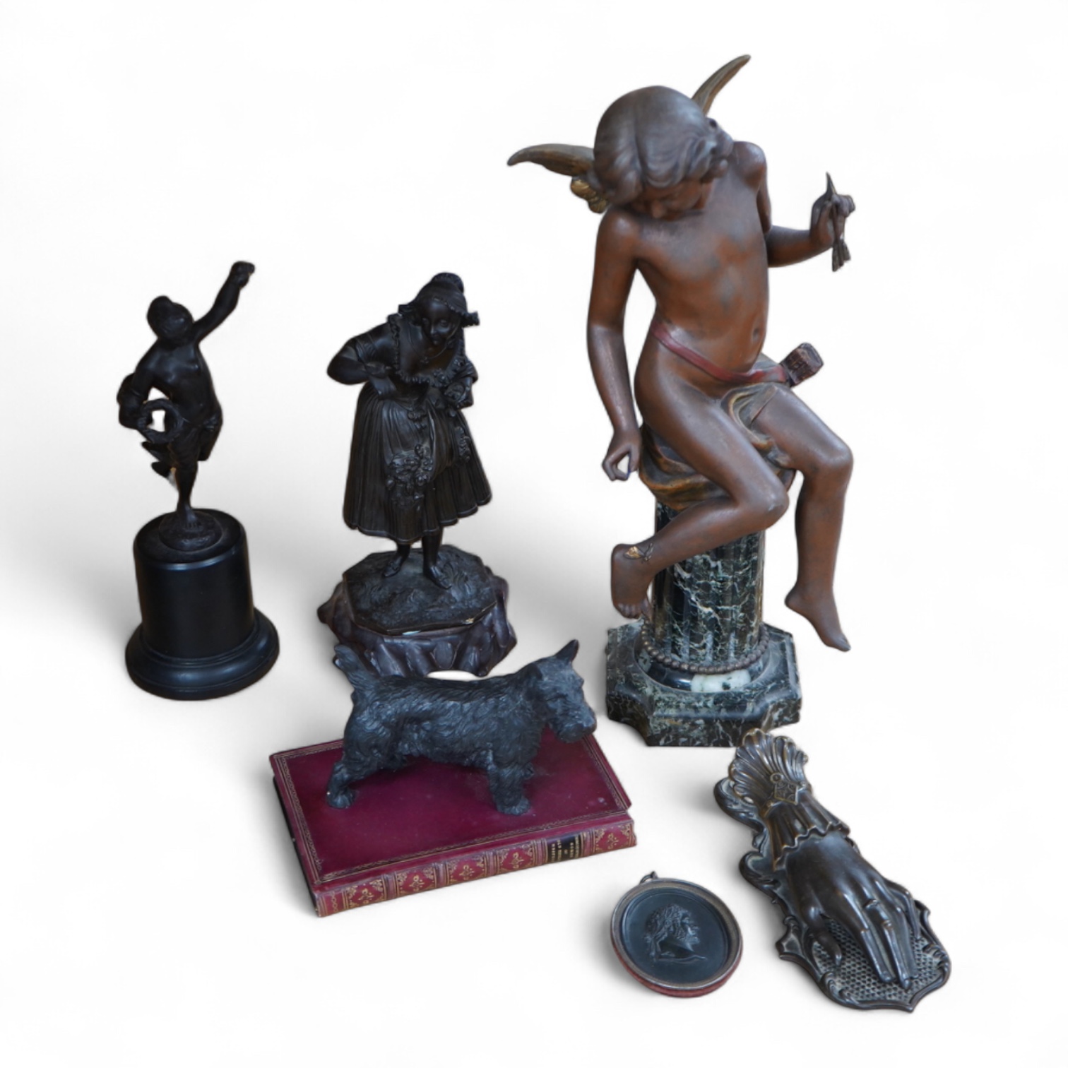 A bronzed spelter angel on column plinth, 38cm high, two other figures, a model of a dog on a book, a letter clip and an oval classical plaque. (6).